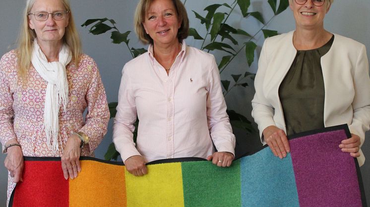 - I Nora kommun vill vi skimra i regnbågens alla färger. Alla är välkomna, säger Solveig Oscarsson (s) när hon, med Margareta Eriksson (s) och Ulla Bergström (s) på var sin sida, rullar ut regnbågsmattan i Tingshusets entré.