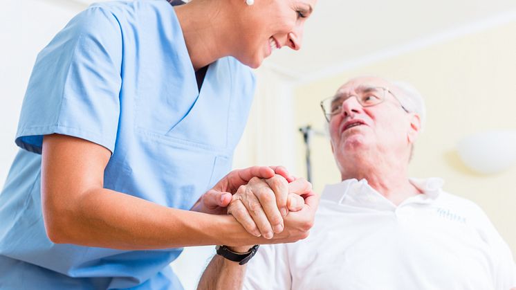 Sjuksköterska håller hand med patient.