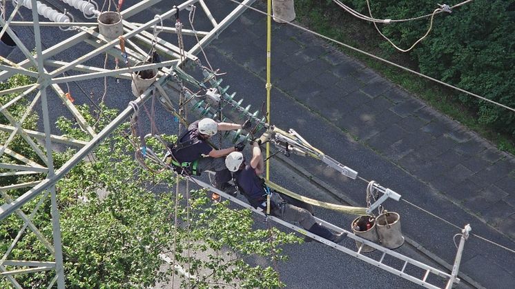 Aus der Drohnenperspektive: Maximilian Selge (links) und Carsten Hartwich lösen die alte 110.000 Volt-Abspannkette, nachdem sie diese zuvor mit Hilfe eines Kettenzuges entlastet haben. Foto: SH Netz