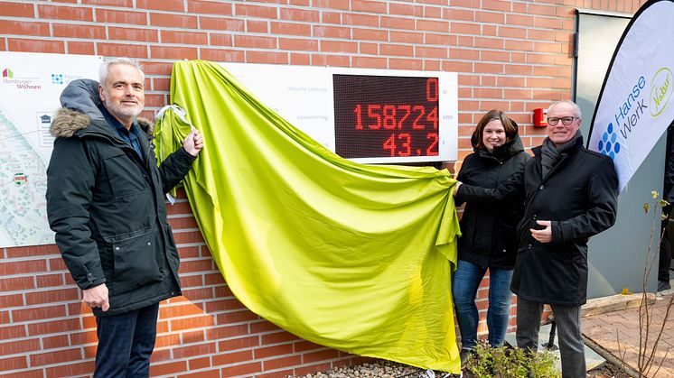 Andreas Breitner, Direktor des Verbands norddeutscher Wohnungsunternehmen (VNW), Sandra Koth, Vorstandsmitglied der Baugenossenschaft Hamburger Wohnen eG und Andreas Marake von HanseWerk Natur (v.l.) enthüllen die Energietafel. 
