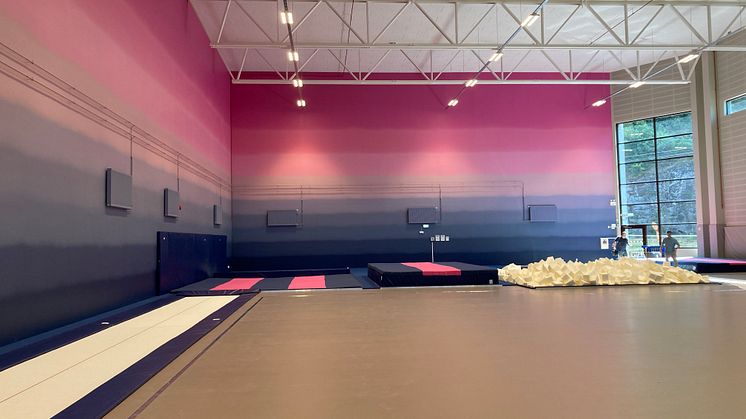 Hall för truppgymnastik med högt i tak och särskild färggradering på väggen, för gymnasternas möjlighet att orientera sig i luften.