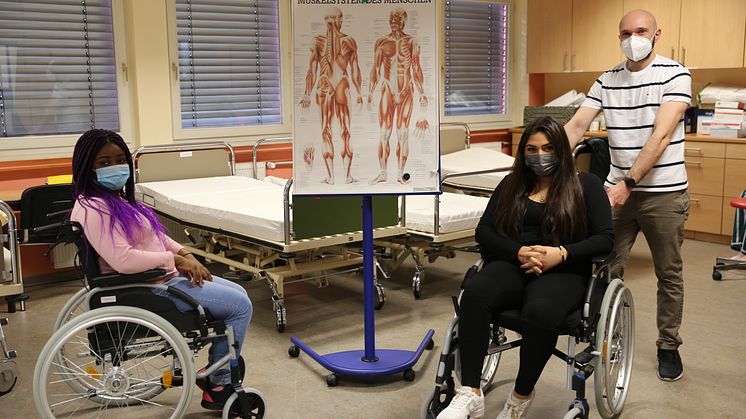 Juvenile Monga (von links), Ilayda Kocak und Nikolai Zittel üben den Umgang mit dem Rollstuhl in der Pflegeschule an der Hephata-Akademie.