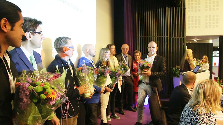 Johan Lindholm, ordförande i Riksbyggen, delar ut blommor till stipendiaterna.