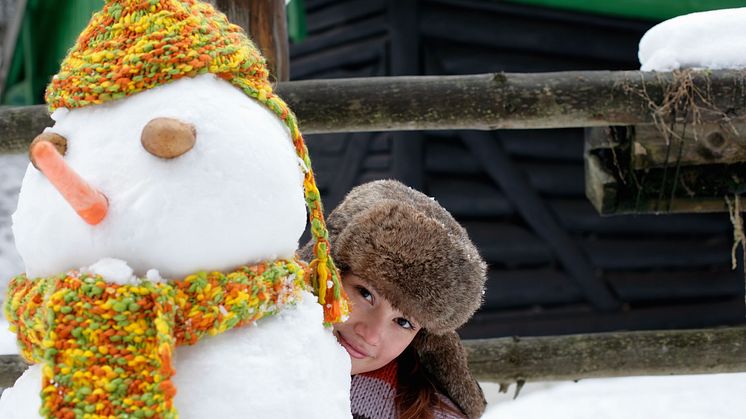 Junge Frau mit Fellmütze hinter Schneemann.jpg