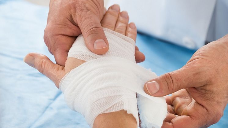 Hand som får bandage.