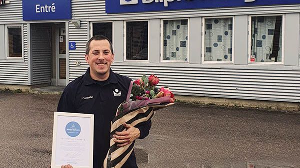 Christoffer Lindberg som är besiktningstekniker på Bilprovningen i Uppsala-Fyrislund firas med diplom och blommor eftersom han utsetts till månadens medarbetare i företaget.