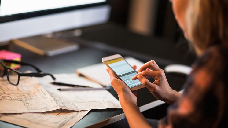 Businesswoman using smart phone-blue prints-Geber86_GettyImages-538082891