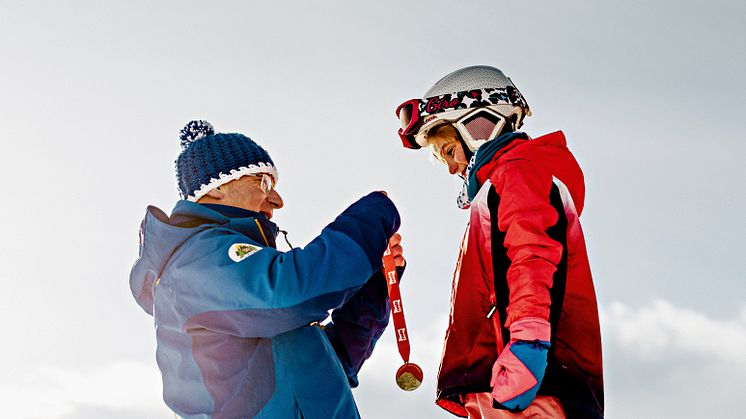 Skischulleiter Noldi Heinz überreicht einem Skischüler eine Medaille, Arosa Skischule, Arosa-Lenzeheide (Graubünden)