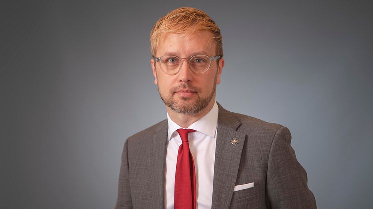 Porträtt på man med glasögon och röd slips. 