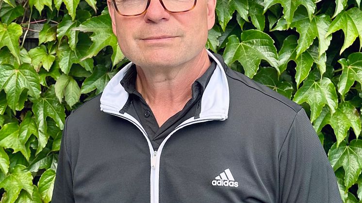 Porträttbild av Kenth Hultqvist stående framför en grön häck.