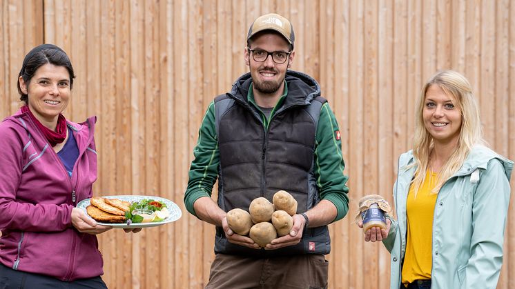Anastasia Rempel vom Hofgut Richerode präsentiert den Richeröder Kartoffelpuffer. Arbeitsgruppenleiter David Straßer und Einrichtungsleiterin Jessica Walz zeigen besonders gut geeignete Kartoffeln der Sorte „Jelly“ und das hausgemachte Apfelmus. 