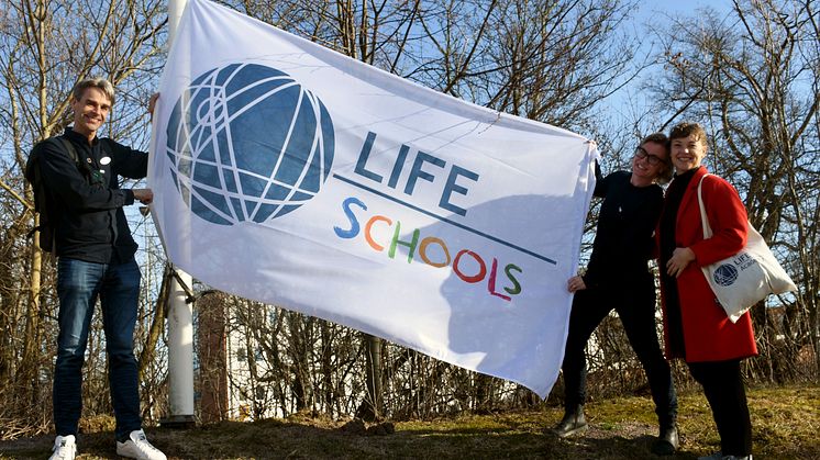 Magnus Köpman, LHU-koordinator och lärare, hissar LIFE School-flaggan tillsammans med Therese Rosenblad och Sara Jansson från LIFE Academy. 