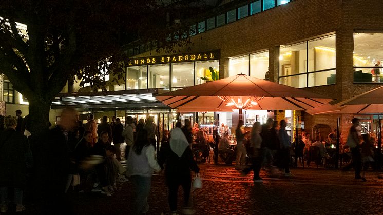 Människor i rörelse kvällstid vid ett torg.