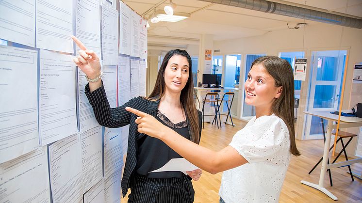Från v. i bild: Suzana Majetic, arbetsmarknadskonsulent, och Thea Hedin står vid AME:s jobbtorg och går igenom några av morgonens nyinkomna jobb. Foto: Daniel Henriksson.