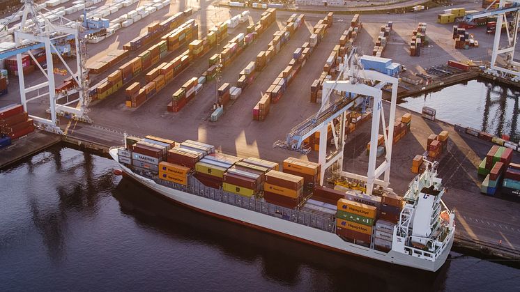 Flygbild över containerterminalen i Helsingborgs Hamn med containerfartyg vid kaj och containrar staplade på terminalytan.