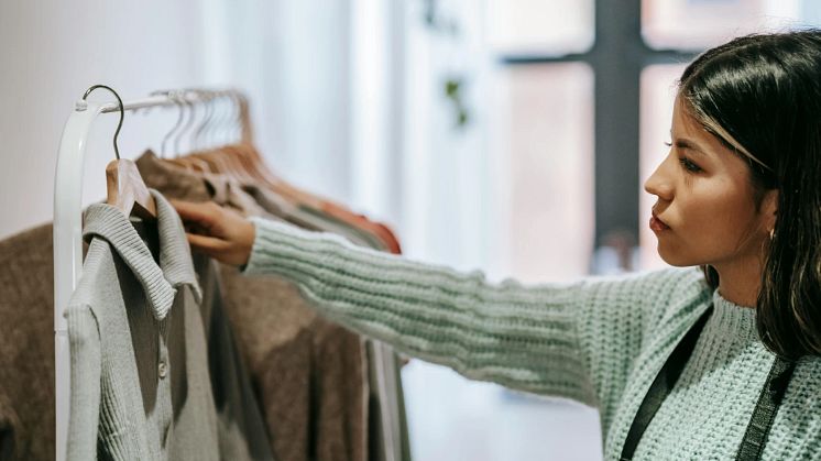 Kvinna i en butik tittar på en tröja som hänger på en galge