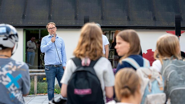 En man som står framför en grupp människor och håller tal.