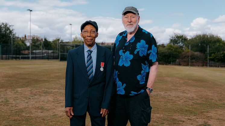 Two people pose for a picture on a cricket pitch