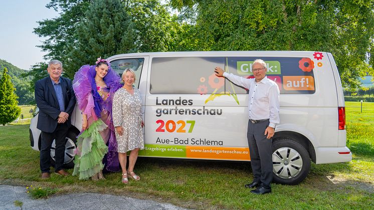 vier Personen stehen vor einen VW-Bus, der mit dem Logo der Landesgartenschau 2027 beklebt wurde