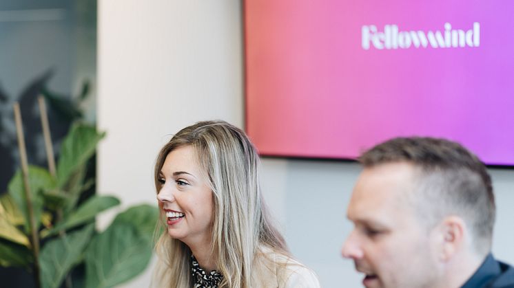 Fellowmind kolleger foran en skærm, hvorpå der står Fellowmind