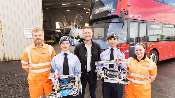 Gateshead cadets with Go North East Engineers and Business Director in front of a bus and plane in aircraft hanger.