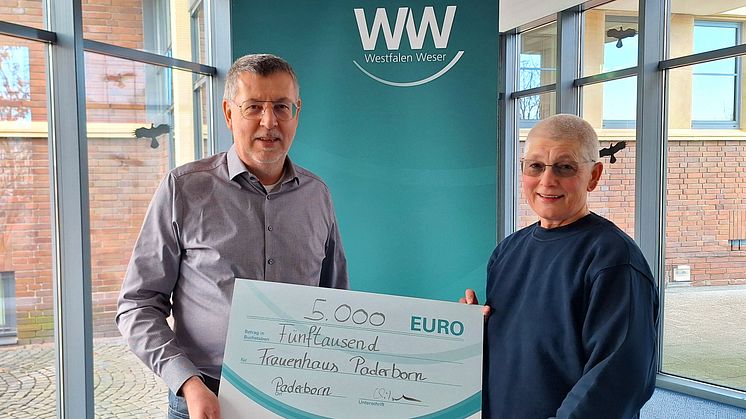Martina Schubert (rechts) vom Frauenhaus Paderborn e.V. nimmt die Spende von Rüdiger Hölscher (links), Kommunalreferent bei Westfalen Weser, entgegen.