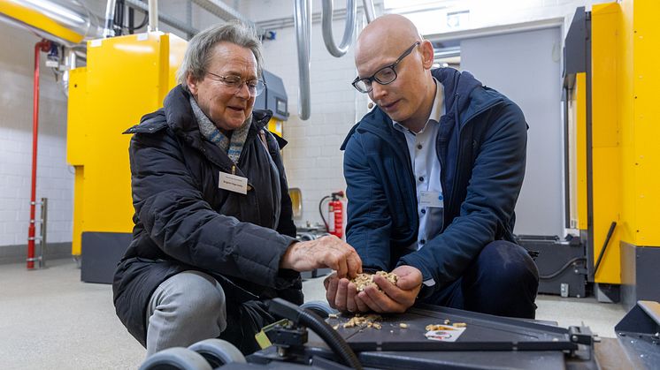Brigitte Vöge-Lesky (l.), Bürgermeisterin der Gemeinde Krummbek, lässt sich von Hendrik Voß (HanseWerk Natur) die Holzpellets zeigen.