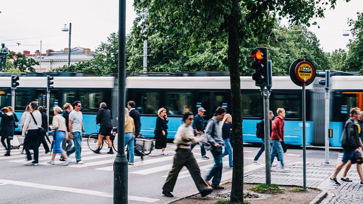 En spårvagn är i rörelse samtidigt som en mängd fotgängare passerar ett övergångsställe