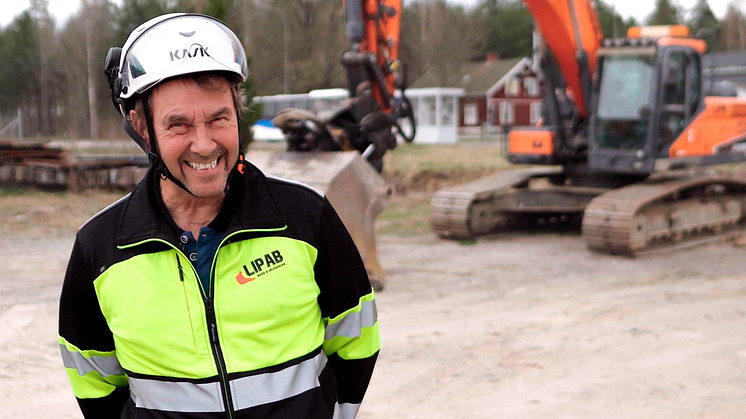 Ingemar Persson, LIPAB:s grundare, framför kontoret i Åsbro med grävmaskin utrustad med L5 Navigations maskinstyrning.