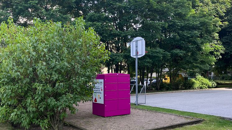 En rosa Pifflbox placerad på en grusad yta omgiven av grönska i Sorgenfri, Malmö.