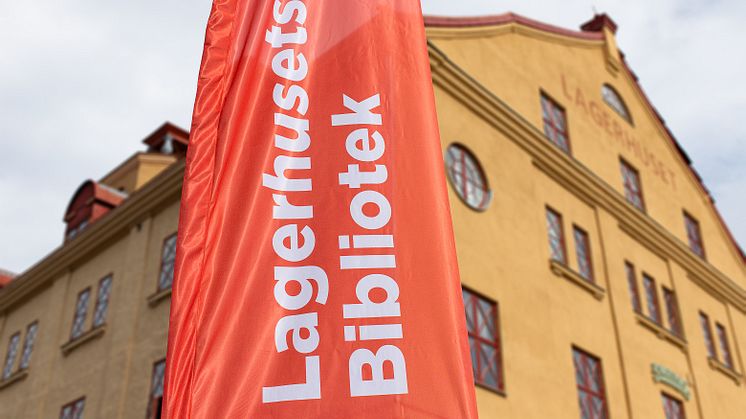 Lagerhuset i Göteborg med en flagga framför med texten Lagerhusets bibliotek. 