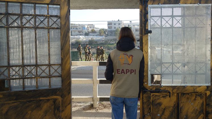 Följeslagare på plats vid porten till en skola där elever dagligen möter israeliska soldater och bosättare.