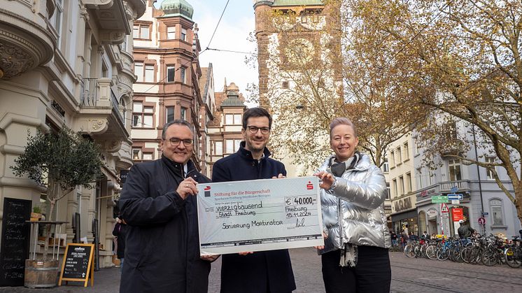 Übergabe des symbolischen Spendenschecks vor dem Martinstor (v.r.n.l.): Andrea Katzer, Amtsleiterin des Gebäudemanagement Freiburg, Freiburgs Oberbürgermeister Martin Horn, Daniel Zeiler, Vorstandsvorsitzender der Sparkasse