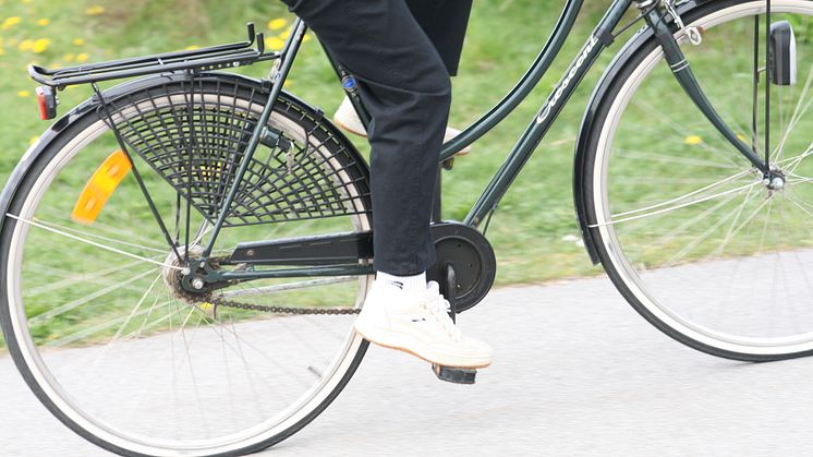 Fötter på pedalerna och bakdäck på en cykel i farten.