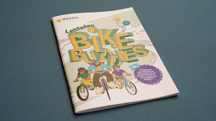 Broschüre "Leitfaden BikeBuddies" auf einem grünen Hocker liegend