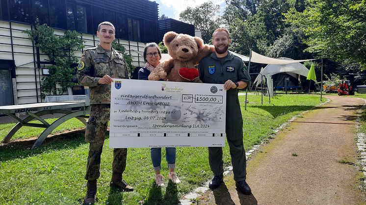 Feldwebel Jim El Hasan, Kerstin Stadler und Major Max Prien präsentieren stolz den Spendenscheck im Bärenherz-Garten