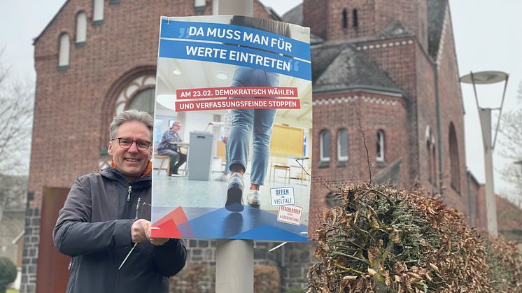 Hephata-Vorstandssprecher Maik Dietrich-Gibhardt bringt das Plakat mit dem Wahlaufruf von "Offen für Vielfalt" neben der Hephata-Kirche an. 