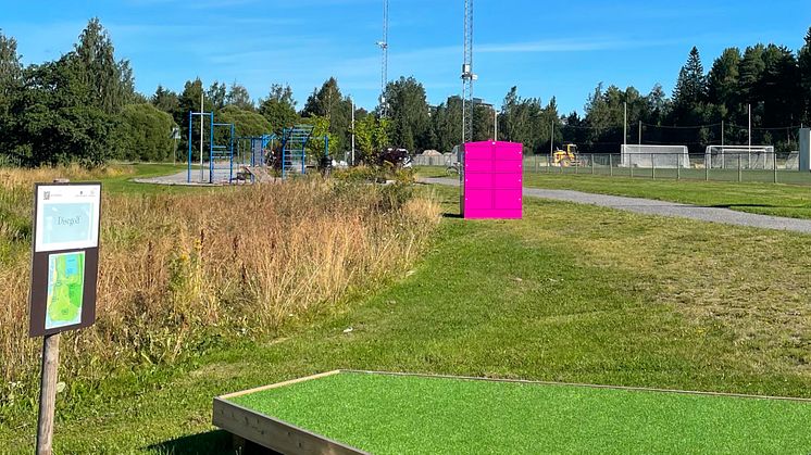 Översiktsbild av en Pifflbox på Campus Umeå, med närliggande utegym, discgolfbana och fotbollsplaner i bakgrunden.
