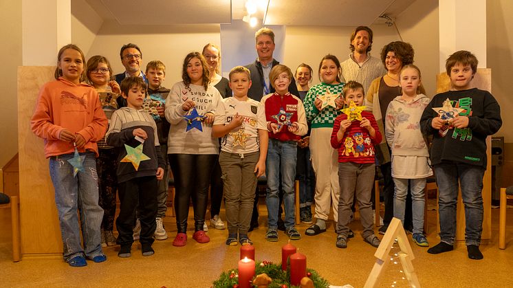 Abholung der Sterne bei der Paul-Moor-Tagesstätte der KJF Donau-Ries in Donauwörth: Kinder und Einrichtungsleiterin Vesna Milijic (mittlere Reihe rechts) präsentieren den LEW-Vertretern (hintere Reihe) ihre mit Wünschen versehenen Sterne.