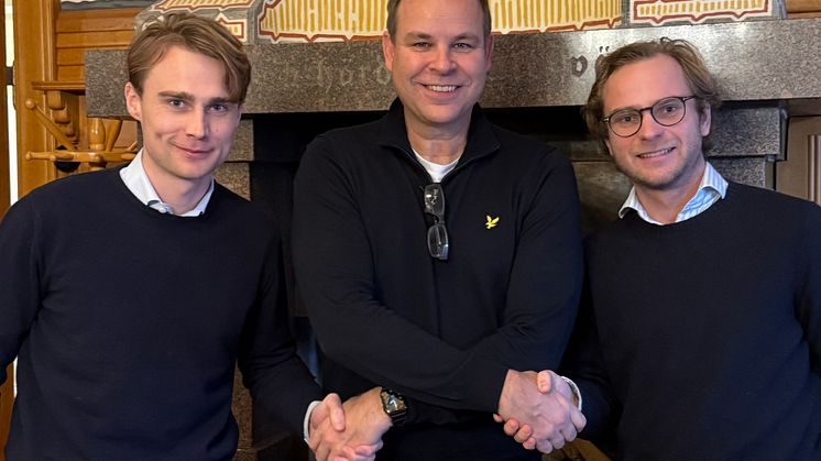 Ägarnas representant flankeras av köparna.