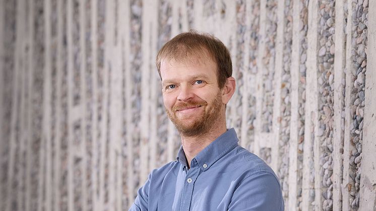 Portrettbilde av mann som smiler iført blå skjorte