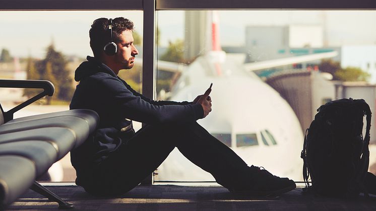 Resenär på flygplats väntar på avgång med flygplan i bakgrunden.