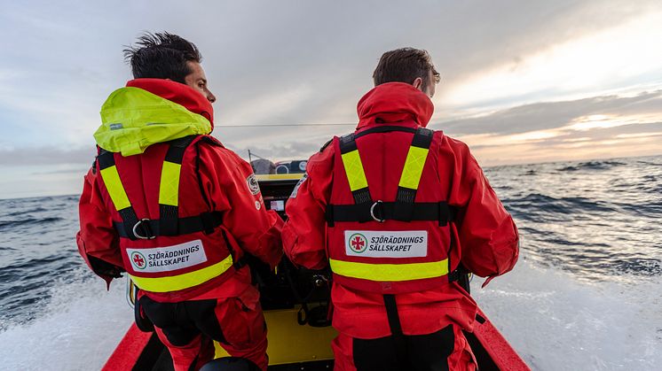 Två sjöräddare ombord på en räddningsbåt med ryggarna vänta mot kameran