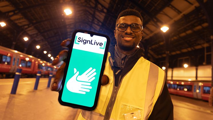 Brighton gateline staff member Mo Ali poses for a picture with the SignLive app which Govia Thameslink Railway now offers for free at all 236 of its managed stations, trains and contact centres for customers who are deaf or have hearing loss