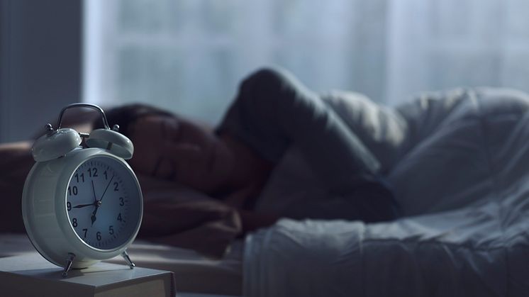 A sleeping woman with an alarm clock at her bedside
