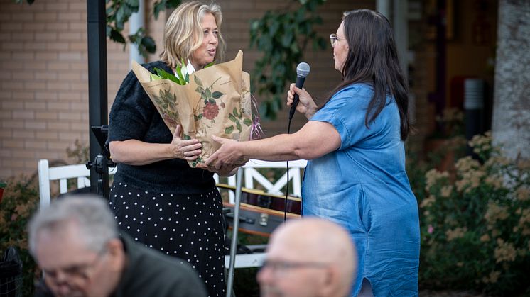 Vård- och omsorgsnämndens ordförande Johanna Karlsson (S) räcker över en blomma till Ann Lagerqvist, enhetschef Norrgläntan.