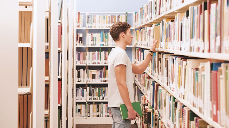 Ein Student sucht ein Buch in der Bibliothek