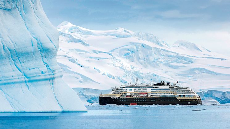 A HX ship is pictured between Antarctica, between two large icebergs in Antarctica. 