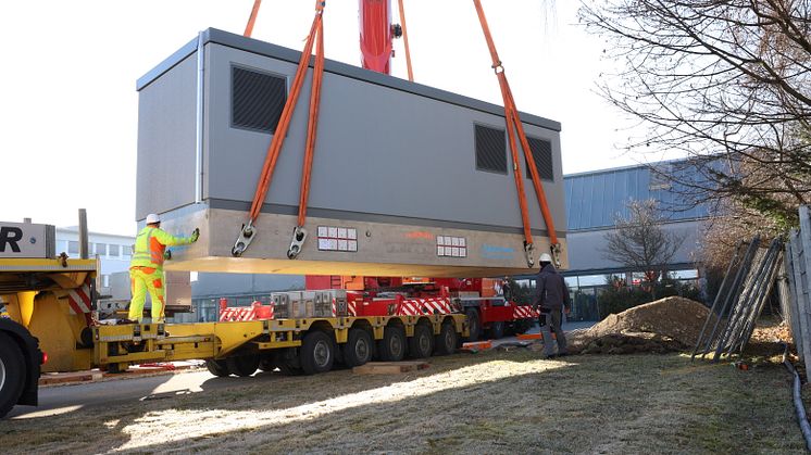 Zentimetergenau auf den neuen Arbeitsplatz: Mit Hilfe eines Spezialkrans setzen Kollegen der Bayernwerk Energietechnik eine von drei neuen Trafostationen beim Maschinenbauer Kiefel ab.