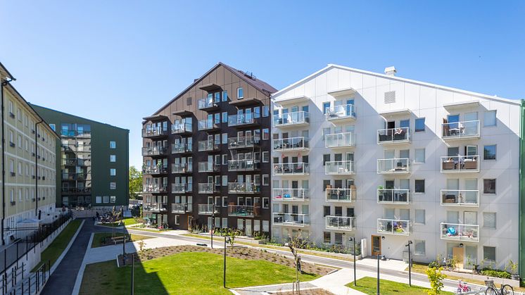 Gård omgiven av fyra huskroppar, en vit, brun och grön nybyggd samt en ljusgul något äldre. 